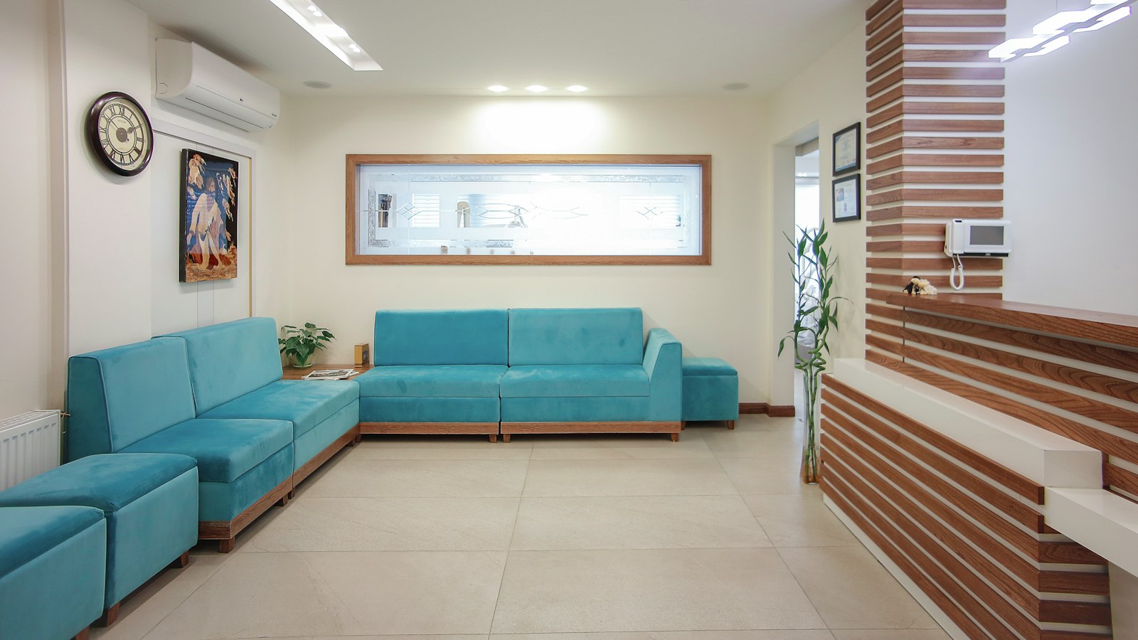 Ruang tunggu klinik dengan sofa toska, panel kayu, dan pencahayaan yang lembut