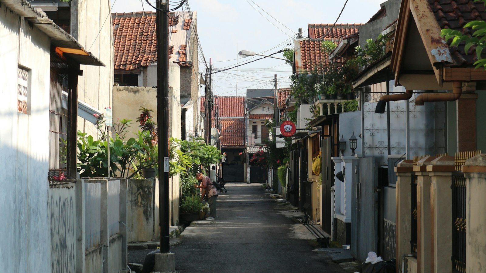 Gang sempit di permukiman padat dengan rumah berdempetan dan tiang listrik