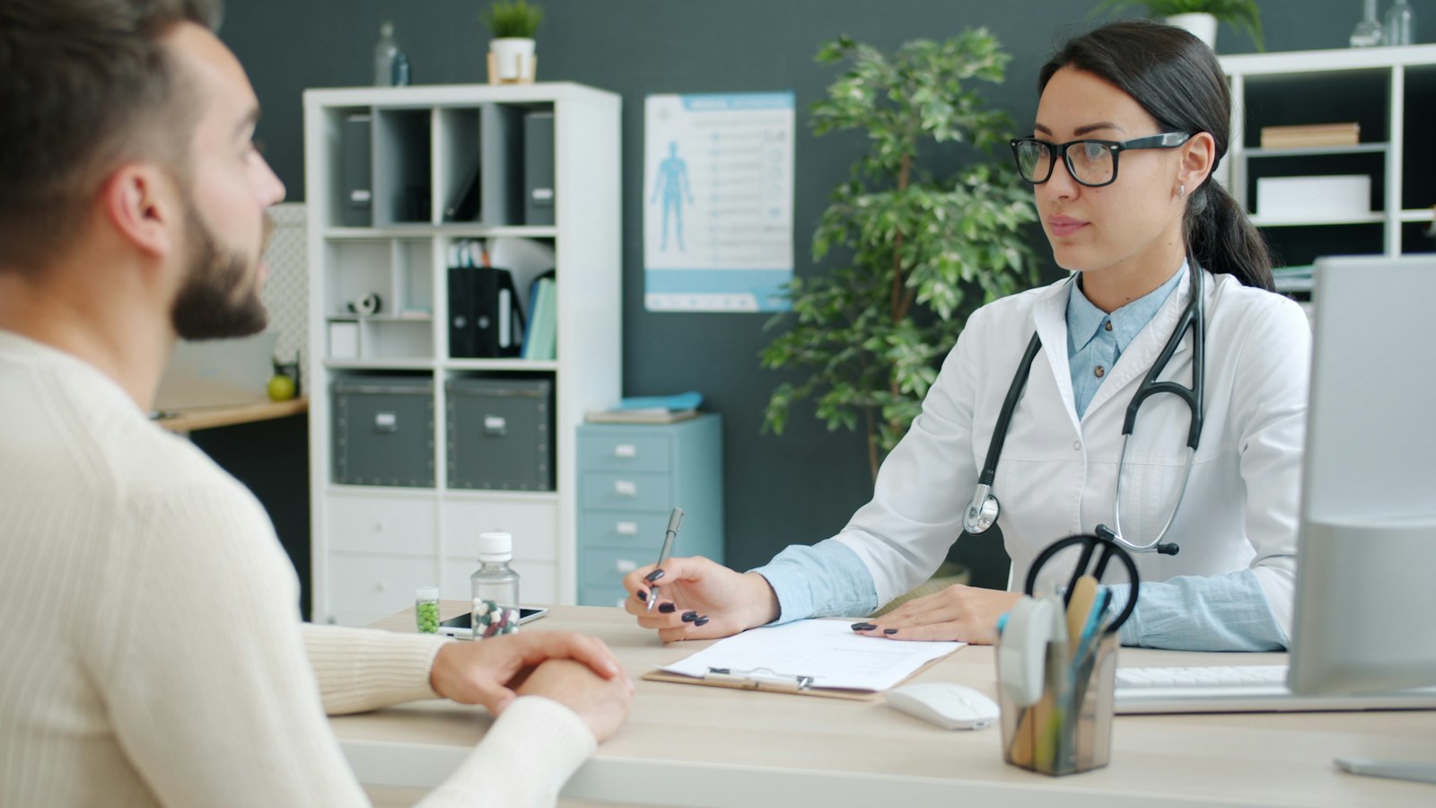 Dokter berkonsultasi dengan pasien di ruang konsultasi yang terang